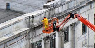 a worker on a lift working on the statehouse exterior 